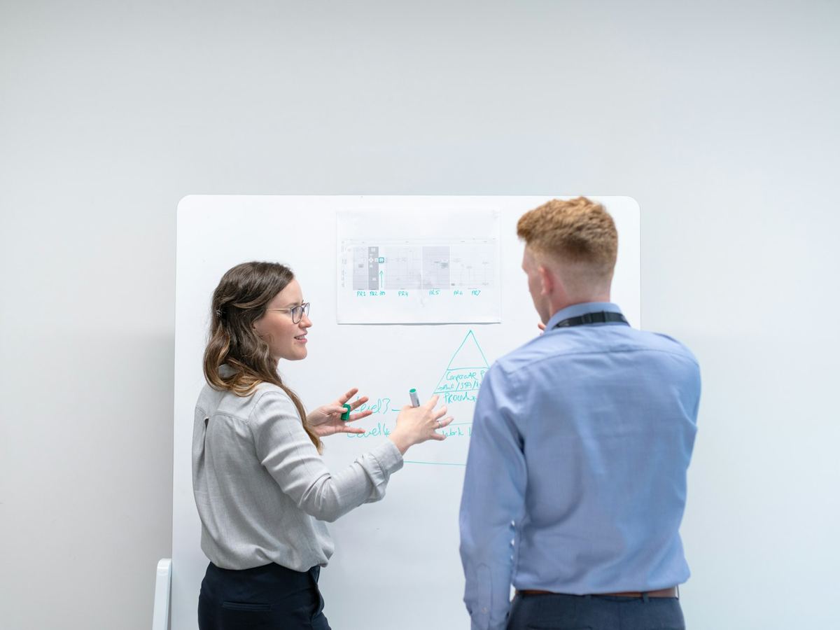Deux collègues travaillent un schéma sur un tableau blanc.